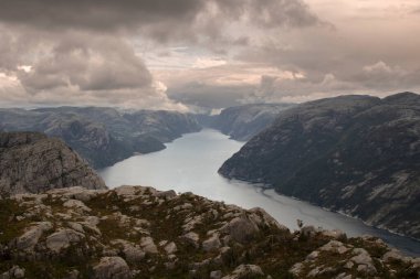 Lysefjord 'u ve etrafındaki dağları gösteren muhteşem bir manzara. Bulutlu bir gökyüzünün altında Preikestolen turist minber kayasına giden yürüyüş rotasında.