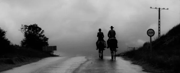 キューバの道路で馬に乗っている人のカップルと黒と白の背景に曇った空 — ストック写真