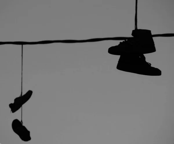 Silhouetten Van Een Paar Schoenen Hangend Aan Een Draad Straat — Stockfoto