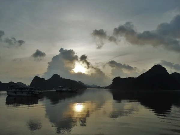 Sunset, mountains and a boat reflection on the water in Ha Long Bay in Vietnam