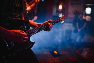 Gitarist silueti sahnede. Koyu arkaplan, duman, spot ışıkları