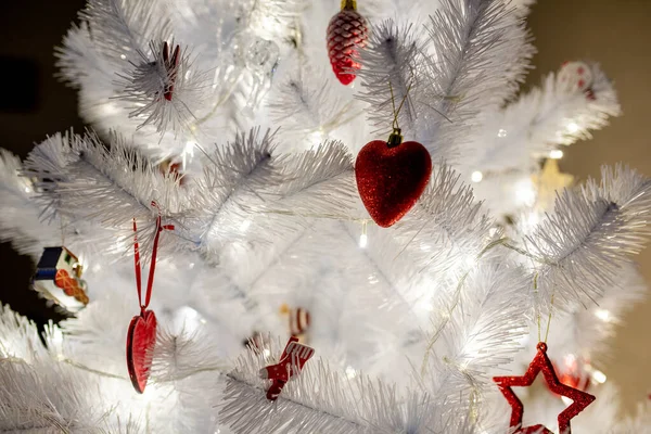 赤いおもちゃの背景を持つ白いクリスマスツリーを閉じる暖かく導かれた閉じる — ストック写真
