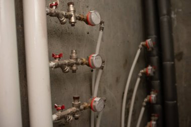 Beyaz beton duvardaki su sayaçları ve vanalar. Binanın pirinç borusuna su sayaçları yerleştirildi.