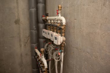Beyaz beton duvardaki su sayaçları ve vanalar. Binanın pirinç borusuna su sayaçları yerleştirildi.