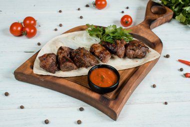 Ahşap masada kırmızı domates soslu kebap seti.