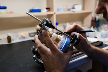 Diş teknisyeni, diş laboratuarında eklem makinesi ile çalışıyor.