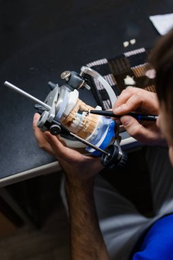 Diş teknisyeni, diş laboratuarında eklem makinesi ile çalışıyor.