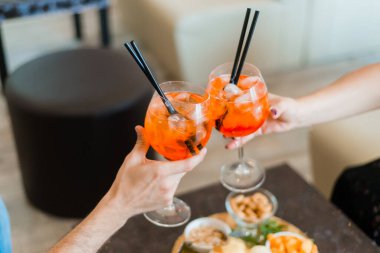 Kafede elinde aperol spreyli kokteyl bardakları olan kadınlar. Geleneksel Spritz aperatifi.