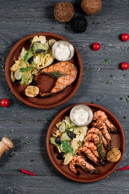 Gri servis masasında kızarmış somon ve karides. Geleneksel yemek menüsü bir restoranda servis edilir. en üstteki görünüm