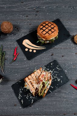 Peynirli burger ve sandviç gri servis masasında. Geleneksel yemek menüsü bir restoranda servis edilir