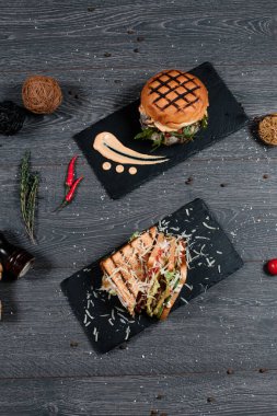 Peynirli burger ve sandviç gri servis masasında. Geleneksel yemek menüsü bir restoranda servis edilir