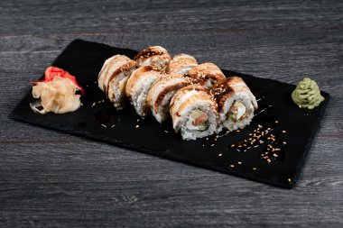 Lokantada siyah tabakta lezzetli suşi rulosu. Gri masa arkasında.