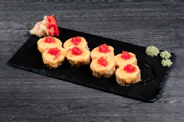 Lokantada siyah tabakta lezzetli suşi rulosu. Gri masa arkasında.