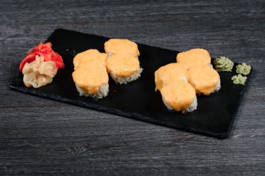 Lokantada siyah tabakta lezzetli suşi rulosu. Gri masa arkasında.