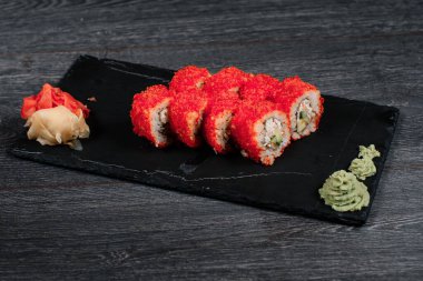 Lokantada siyah tabakta lezzetli suşi rulosu. Gri masa arkasında.