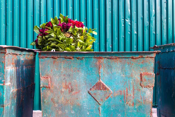 Big bouquet of flowers in the street trash can. High quality photo