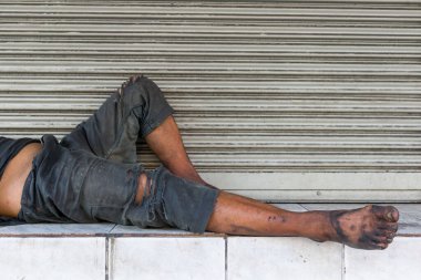 Fakir evsiz bir adam ya da mülteci şehirdeki şehir sokaklarındaki ahşap bankta uyuyor..