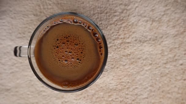 Kávová pěna rotuje v hrnku s hnědým texturovaným pozadím. Video 120 fps. — Stock video