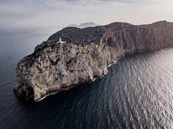 Kuzey Mallorca, İspanya 'nın Balear Adaları kıyısındaki Cap de Formentor' un güzel beyaz deniz fenerinin hava manzarası gün batımında. Vahşi kayalıkların geniş manzarası.