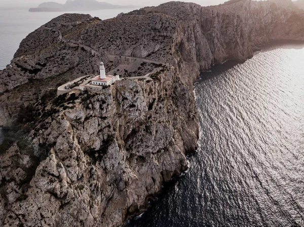 Kuzey Mallorca, İspanya 'nın Balear Adaları kıyısındaki Cap de Formentor' un güzel beyaz deniz fenerinin hava manzarası gün batımında. Vahşi kayalıkların geniş bir manzarası var. Serpentine Yolu