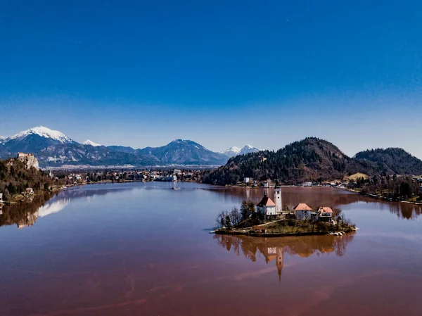 Slovenya 'daki ünlü kırmızı göl ve ada Bled (Blejsko jezero). Maria ve Bled Castle 'ın Hacı Kilisesi ve arka planda küçük bir kasaba olan güzel dağlık dağ gölü..