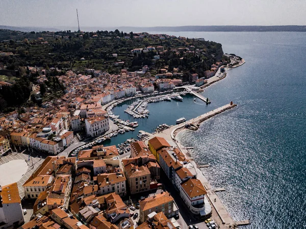 Tartini ana meydanlı Piran kasabası, kırmızı çatılı antik binalar, tekneleri yansıtan Piran limanı ve Slovenya 'nın güneybatısındaki Adriyatik denizi