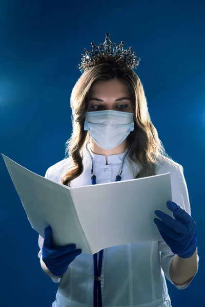 Salgının yayılmasını önleme ve koronavirüs COVID-19 'u tedavi etme kavramı. Korku filmi gibi, maskeli bir doktorun portresi ve eldivenler karanlık mistik atmosferde bilgi broşürü okuyor. 
