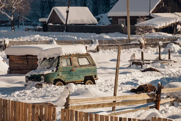 Rus köyü: eski Sovyet off-road arabası karlı avluda ahşap evler ve gübre ile park edilmiş.