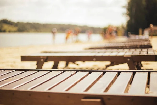 Güneş yatakları sıraları, Bokeh 'in arka planında bir grup turistle kumsalda duruyor.