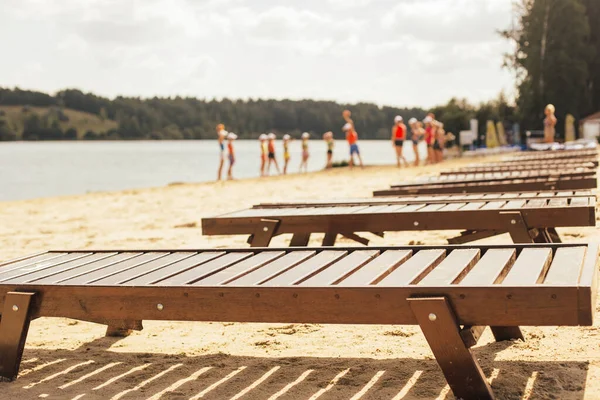 Güneş yatakları sıraları, Bokeh 'in arka planında bir grup turistle kumsalda duruyor.