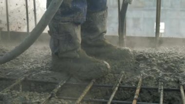 Üniformalı işçiler katı bir yüzey oluşturmak için vibratörü beton kütleye indirirler (beton kütle karışım spreyleri ile beton çalışmaları videosunu kapat)