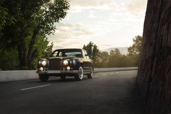 Japon iş otomobili sedan Mitsuoka Galue gün batımında parktaki yolda farları açık halde.