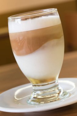 Tahta masada beyaz tabakta buzlu latte.