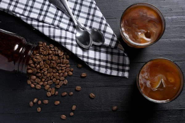 Cold brew coffee in a dark wood table with roasted coffee beans