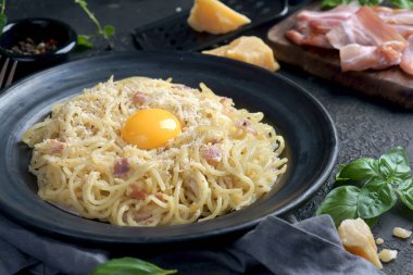 Spaghetti Carbonara, sarısı ve pastırması koyu arka planda.