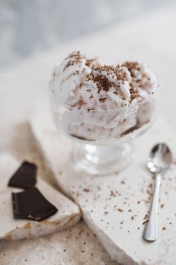 Vanilyalı dondurma, şeffaf bir kâse içinde çikolata parçacıkları serpiştirilmiş.