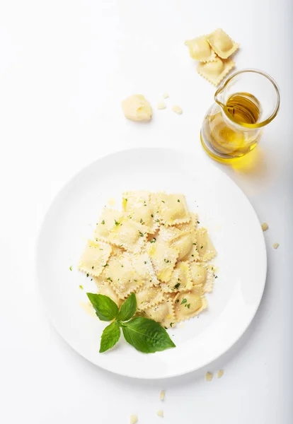 Beyaz arka planda beyaz bir tabakta fesleğen ve parmesanlı Ravioli. Üst Manzara. Beyaz şarap. İtalyan Mutfağı