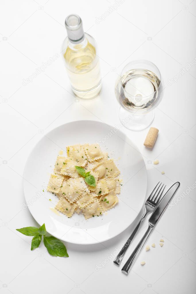 Ravioli with basil and parmesan on a white plate on a white background. Wine. top view. Italian Cuisine