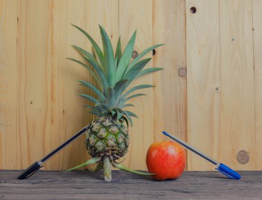 Pen-ananas-elma-kalem ahşap arka plan üzerinde.