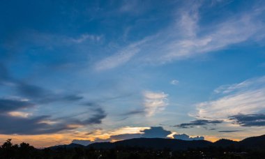 Arkaplanda dağ ve günbatımı görüntüsü.
