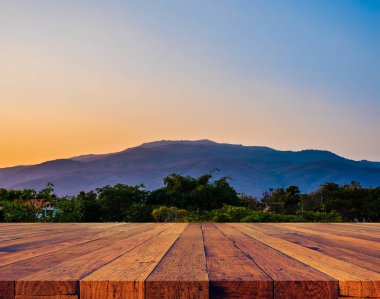 Ahşap masa ve yeşil dağın bulanık görüntüsü.