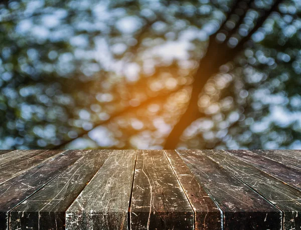 Деревянный стол и размытый образ зеленого дерева  . — стоковое фото