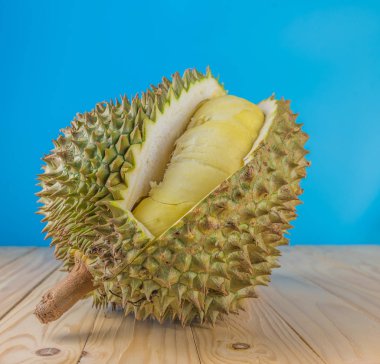 Ahşap masa üzerinde sarı posası olan olgun durian resmi.