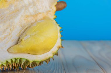 Ahşap masa üzerinde sarı posası olan olgun durian resmi.