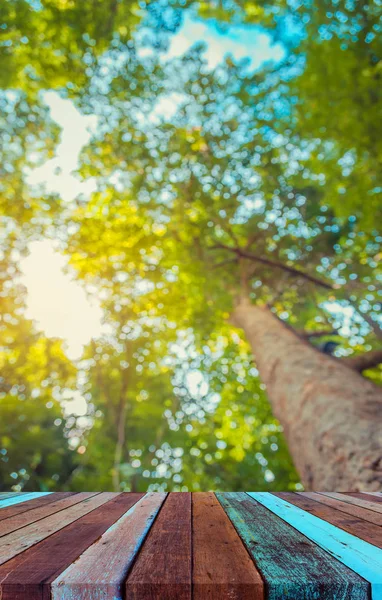 Dřevěný stůl a rozostřit obraz stromu bokeh. — Stock fotografie