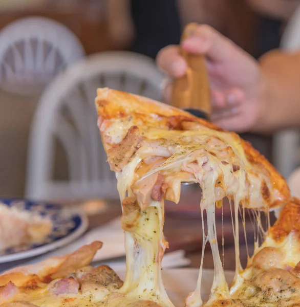 image of hand lift up cheese and ham pizza.