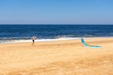 Çocuk kumsala uçurtma fırlatıyor.