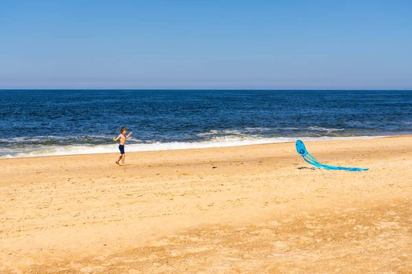 少年はビーチで凧を発射し — ストック写真
