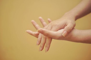 Turuncu arka planı olan el dezenfektanı kullanarak elini kapat..