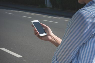 Kadın şehir sokak ışığında beyaz onu iphone ile yürüyor